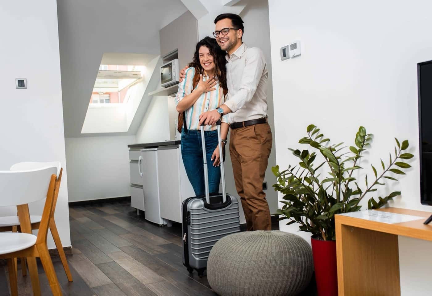 Ein lächelndes Gästepaar kommt mit Koffer im Zimmer an