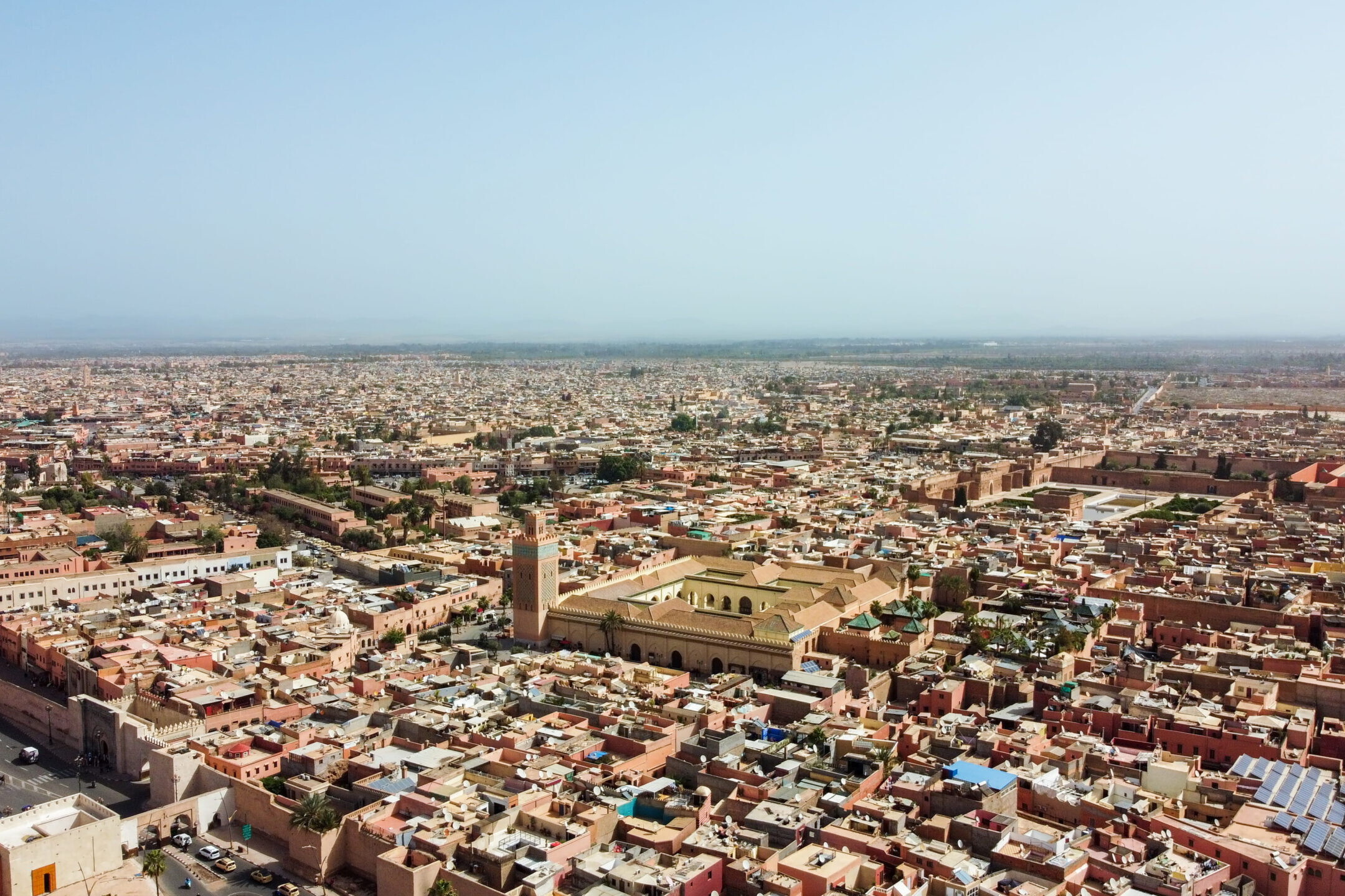 Vue a&eacute;rienne de Marrakech montrant la m&eacute;dina, les remparts et une mosqu&eacute;e au c&oelig;ur de la ville sous un ciel clair.