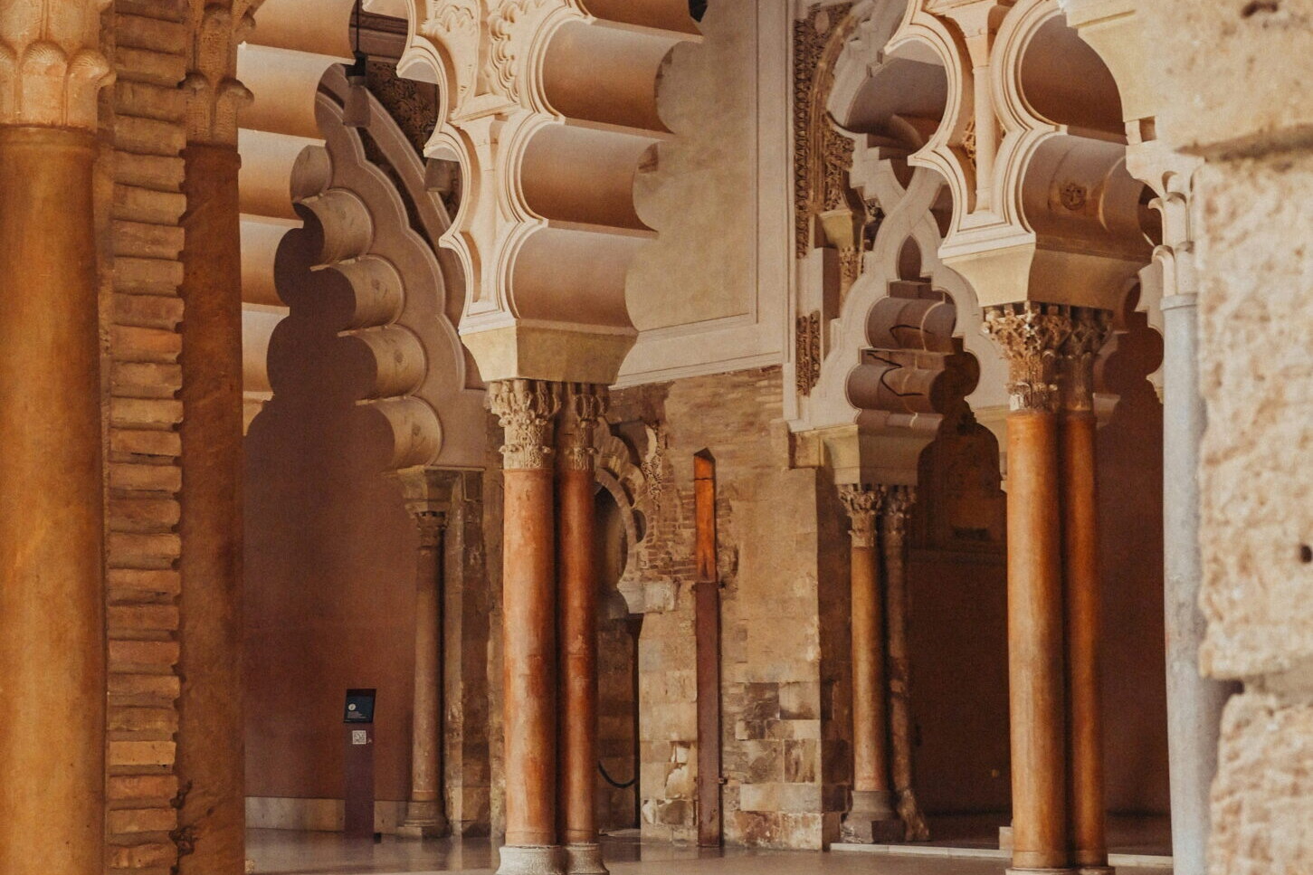 Int&eacute;rieur du palais de l&rsquo;Aljafer&iacute;a &agrave; Saragosse avec arches mud&eacute;jares sculpt&eacute;es et colonnes d&eacute;cor&eacute;es dans un b&acirc;timent historique espagnol.