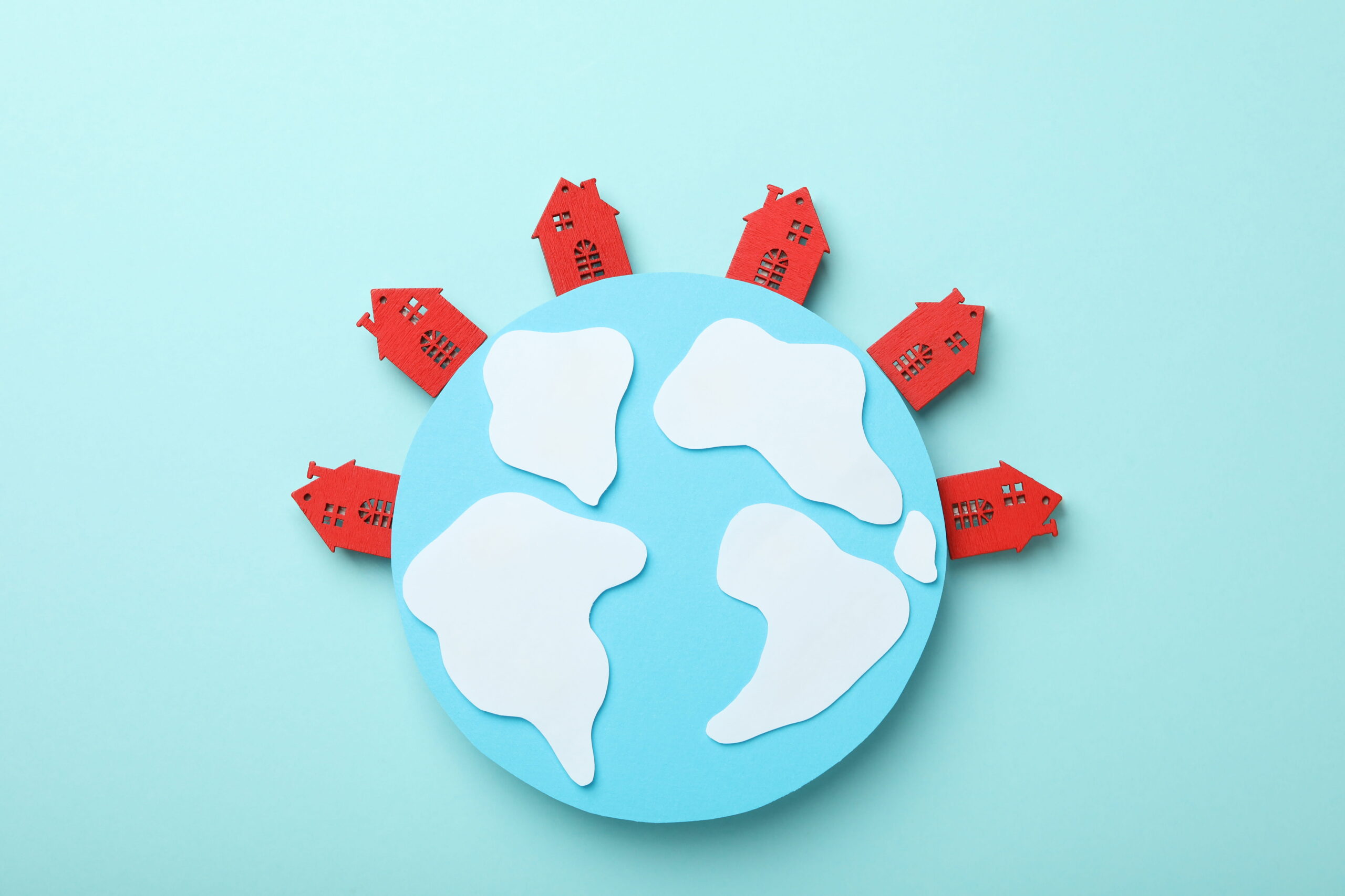 Illustration d’une planète entourée de maisons rouges symbolisant le home exchange et le voyage durable