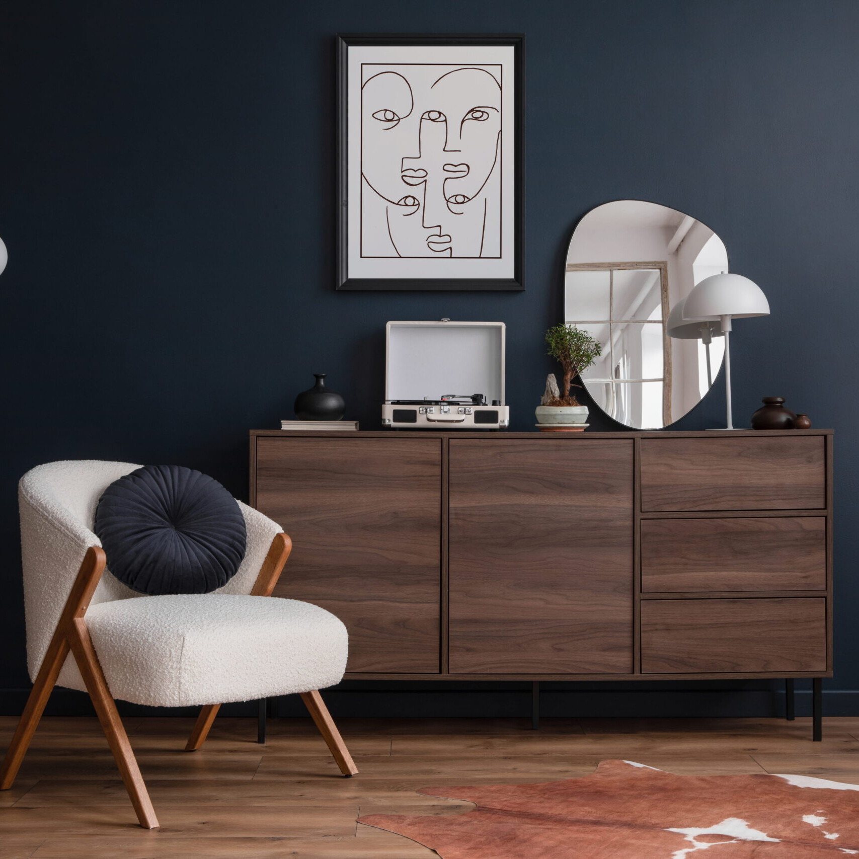 Salon moderne avec mur bleu foncé, meuble en bois, fauteuil design, plantes vertes et décoration intérieure épurée