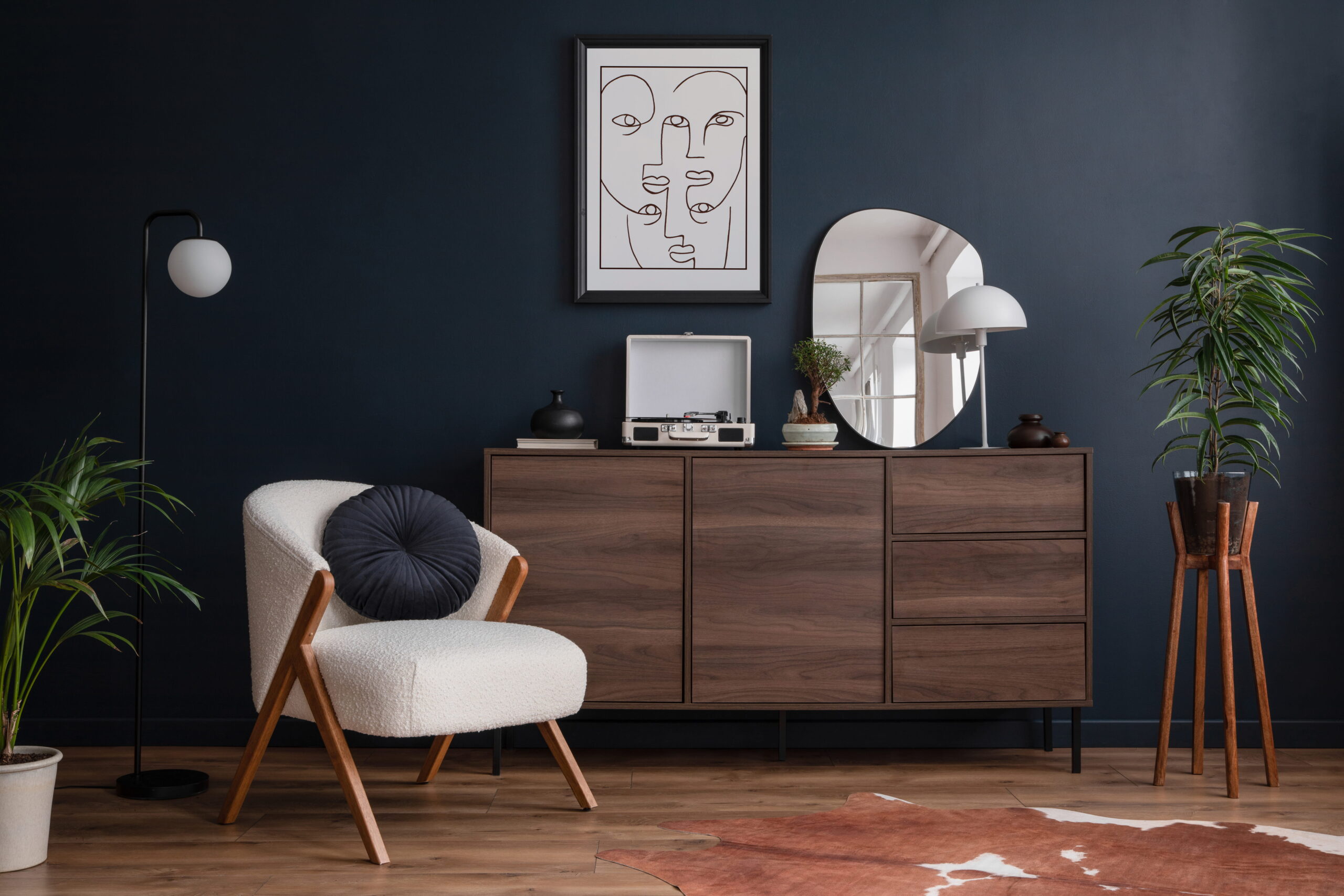 Salon moderne avec mur bleu foncé, meuble en bois, fauteuil design, plantes vertes et décoration intérieure épurée
