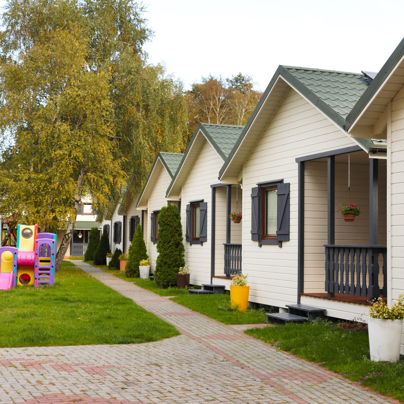 Alignement de cottages dans un village vacances avec aire de jeux pour enfants et espaces verts arborés