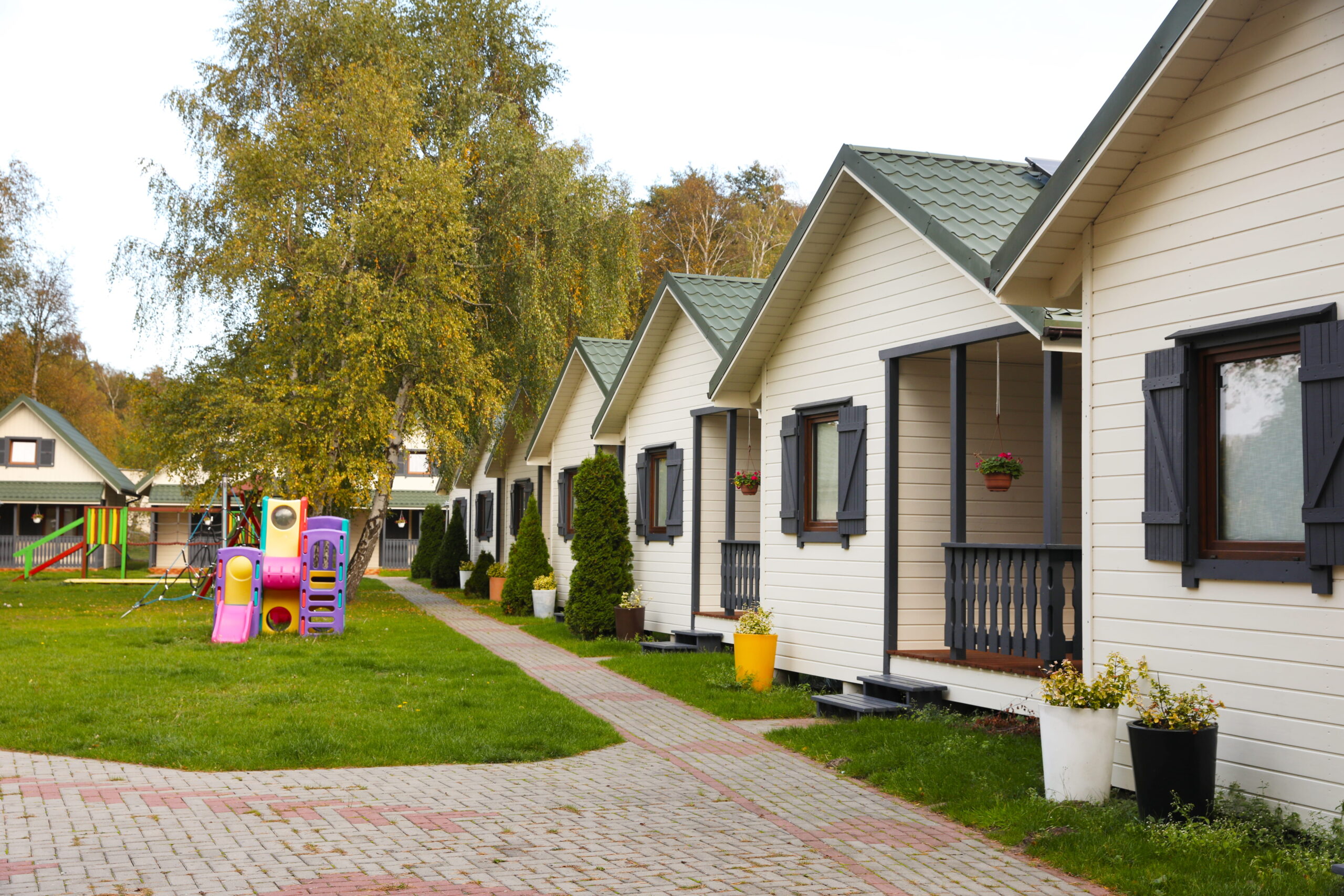 Alignement de cottages dans un village vacances avec aire de jeux pour enfants et espaces verts arborés