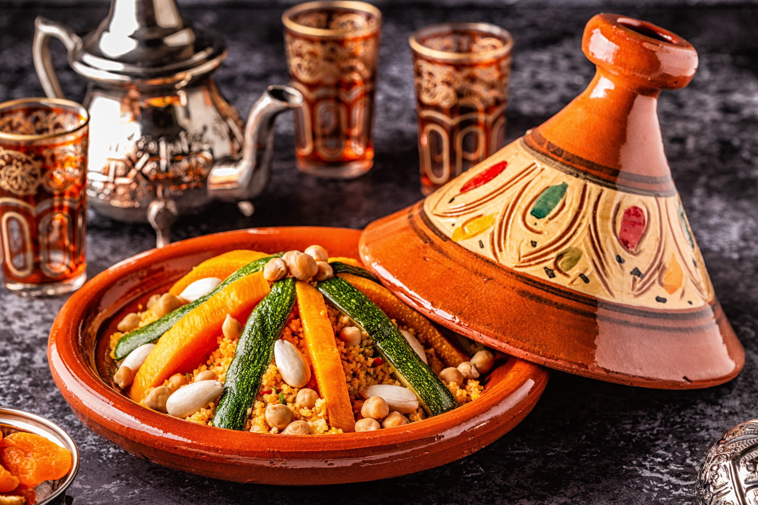 Plat de couscous marocain avec l&eacute;gumes servi dans un tajine en terre cuite avec th&eacute; &agrave; la menthe