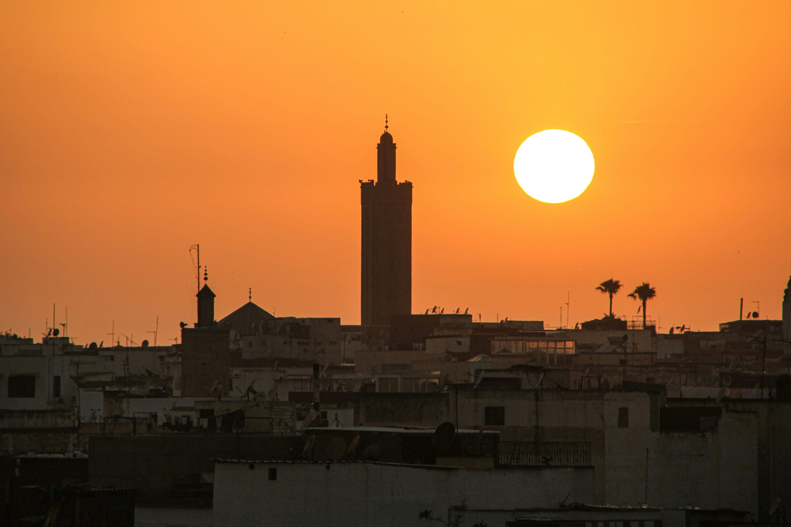 Silhouette d&rsquo;un minaret et des toits de Rabat au coucher du soleil orange