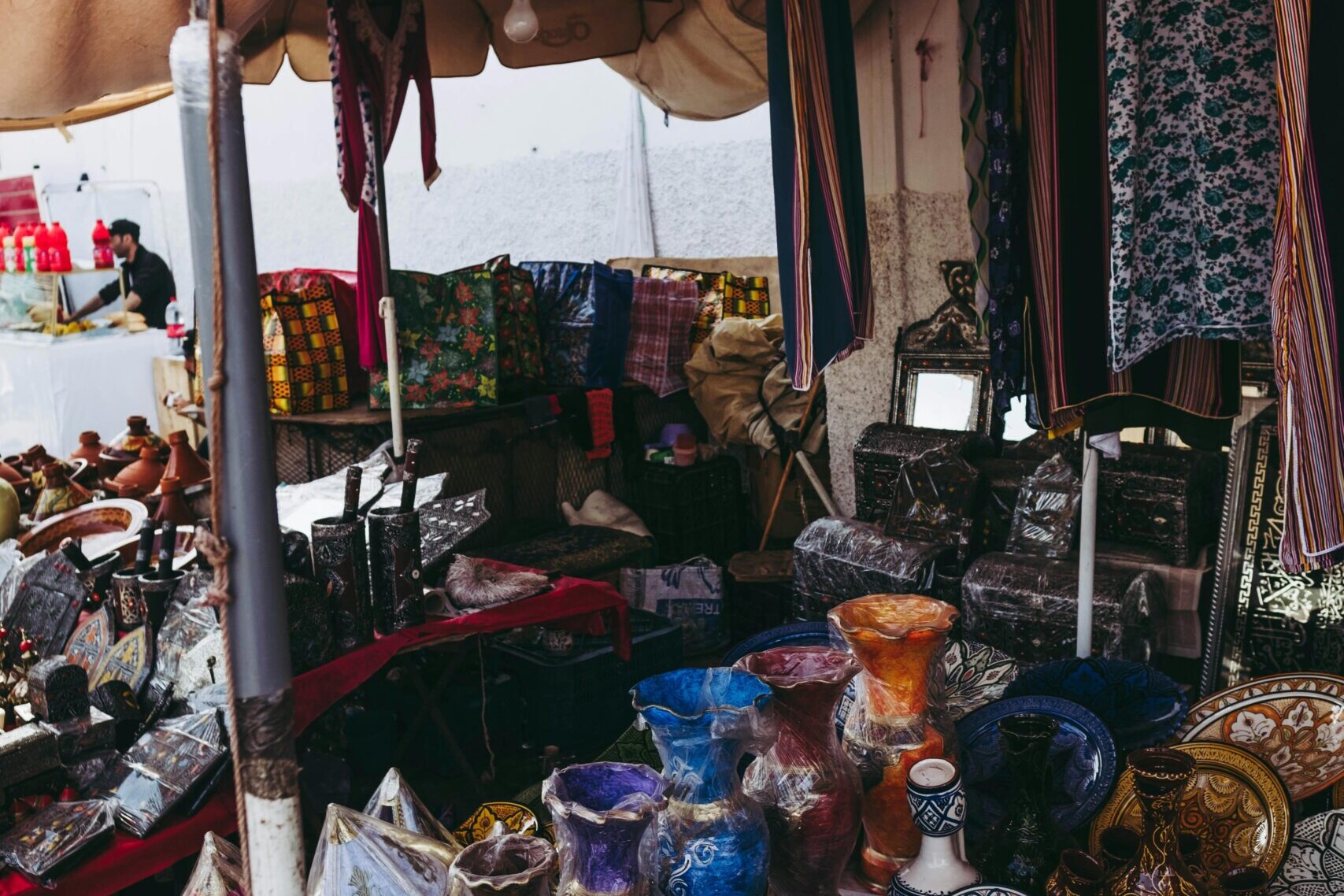 Stand de march&eacute; &agrave; Casablanca avec vaisselle artisanale color&eacute;e et textiles marocains
